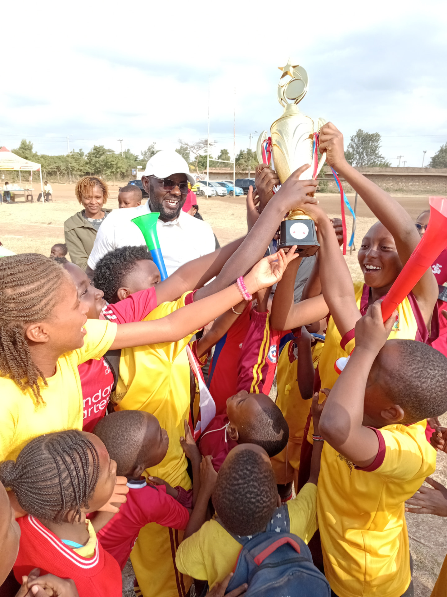 Myfin School players celebrating with a golden trophy raised high