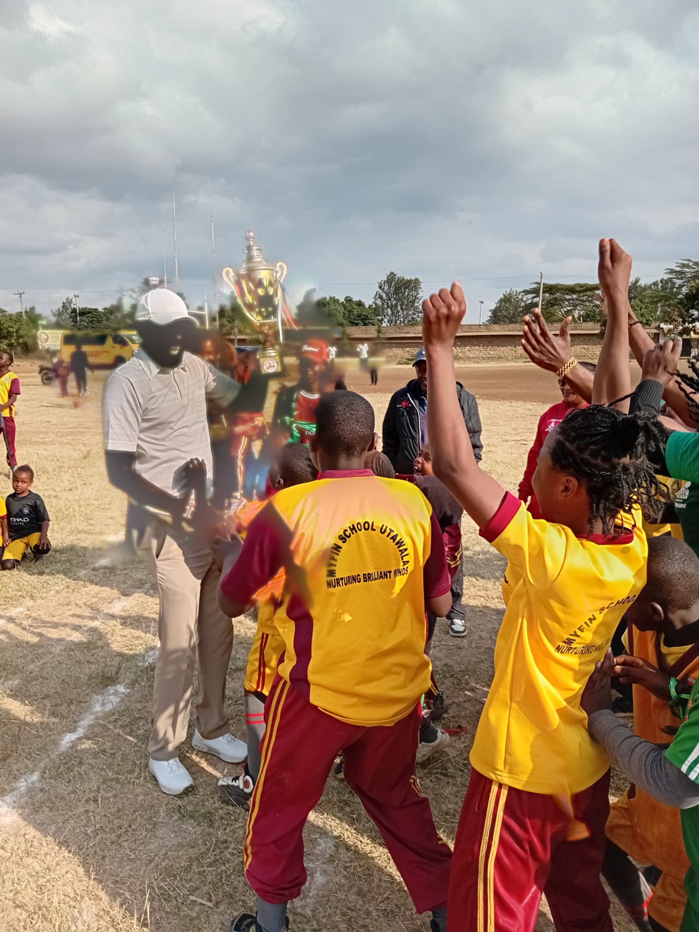 Myfin School Utawala team in yellow and maroon kit cheering after a match win