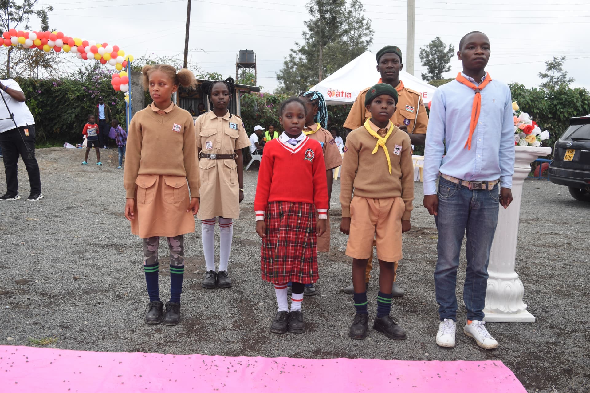 Myfin School scouts standing to attention beside decorated event arch