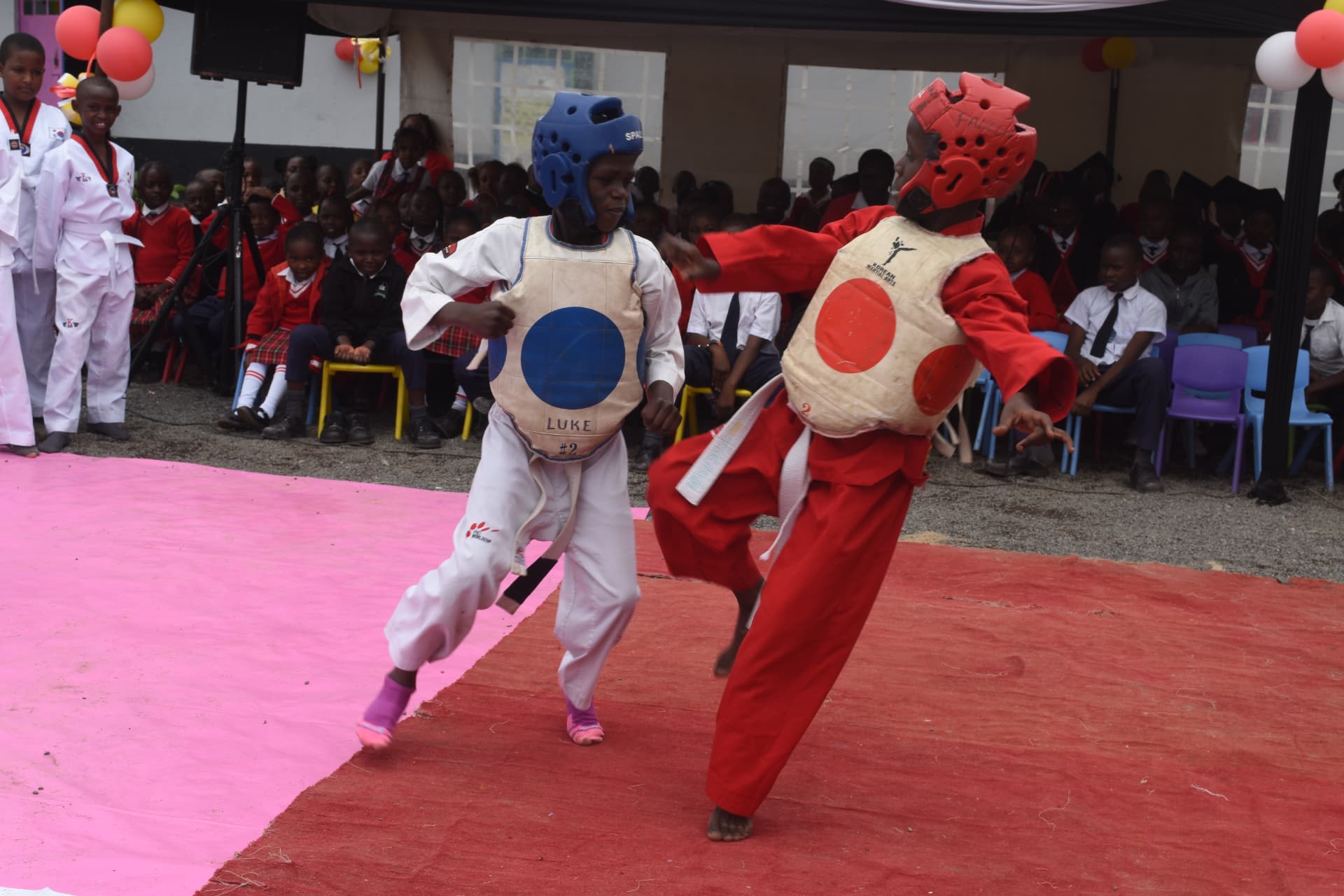 Two Myfin School taekwondo students sparring in protective headgear and body armour