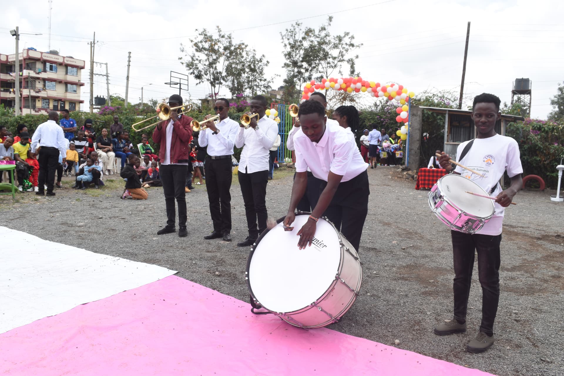 Brass band performing with drums and trumpets at a Myfin School event