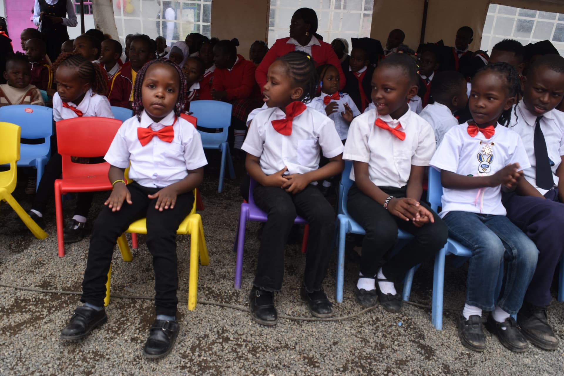 Myfin School learners in white shirts and red bow ties seated at a school event