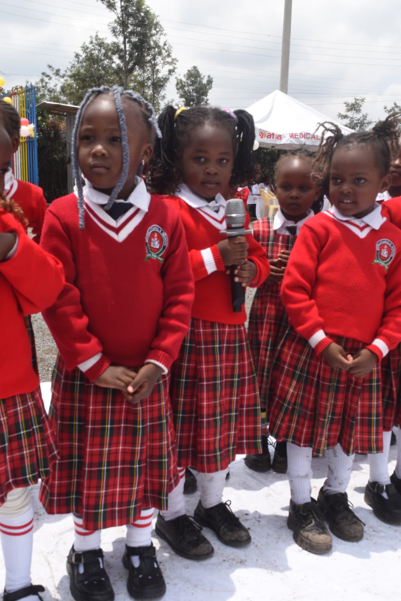 Myfin School early years learners in red jumpers singing into a microphone