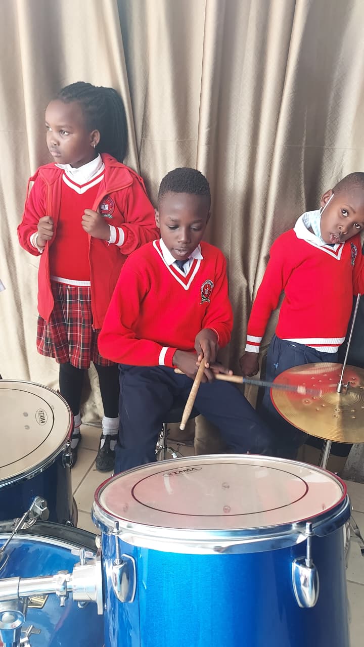 Myfin School learner playing the drum kit while classmates look on during a music lesson