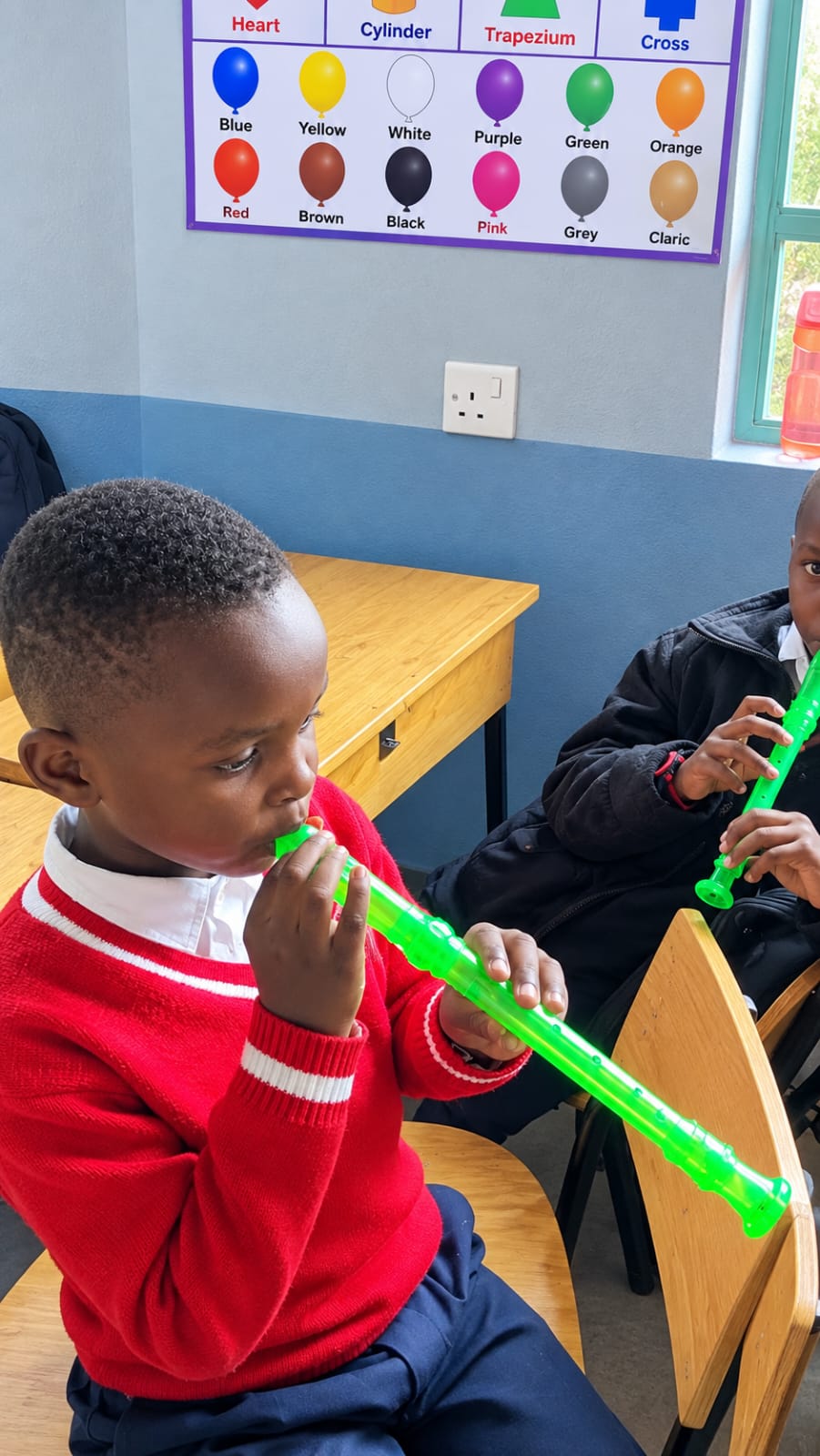 Myfin School learners playing green recorders together at their classroom desks